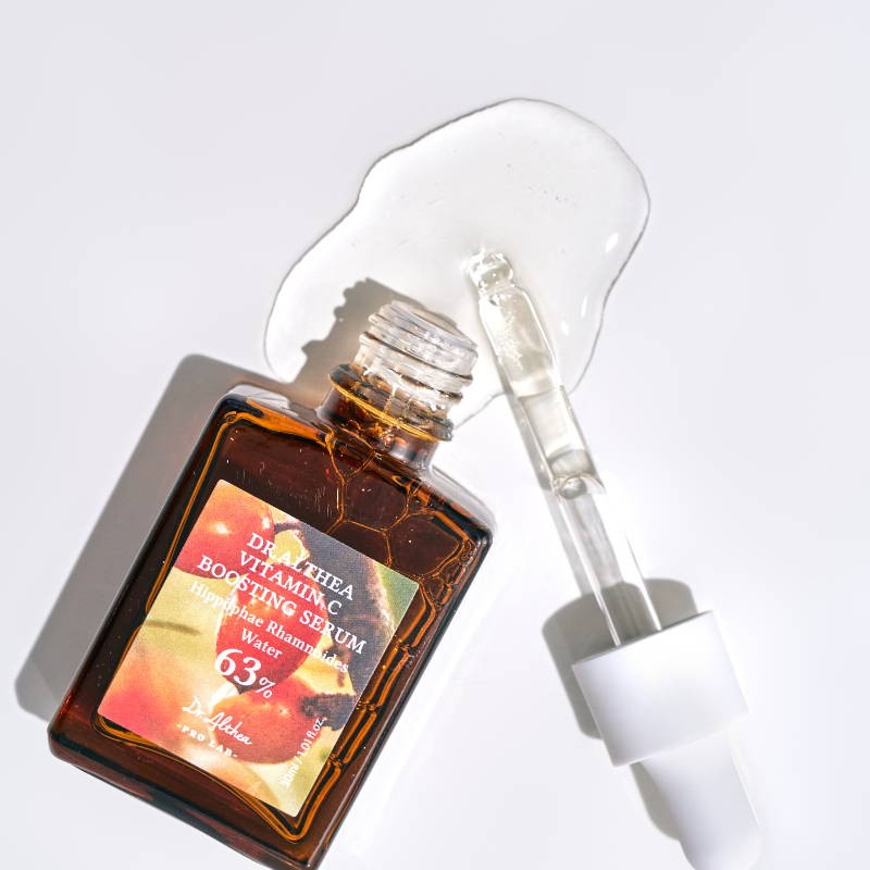Dr Althea Vitamin C Boosting Serum open on white background, spilling onto surface.