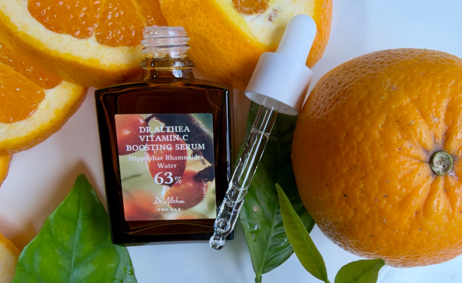 Dr Althea Vitamin C Boosting Serum open on white background, spilling onto surface.