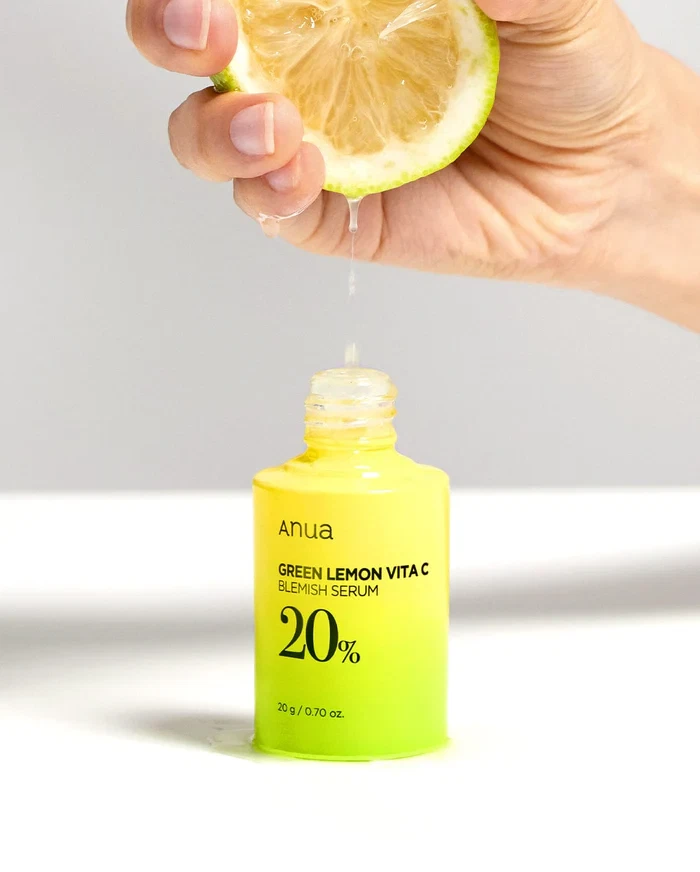 Anua Green Lemon Vita C Blemish Serum with a background of green lemons and glass cubes.